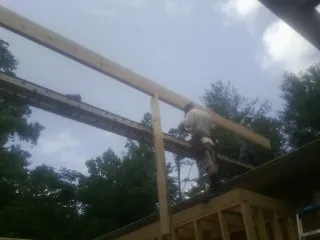 Carpenter setting a ridge beam over a new addition frame — Ice Dam Removal by Roofing Brothers in Calmar