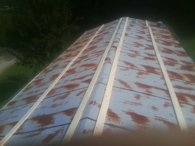Rusted metal roof panels with new wood purlins before replacement — Storm Damage Roof Repair in Calmar by Roofing Brothers