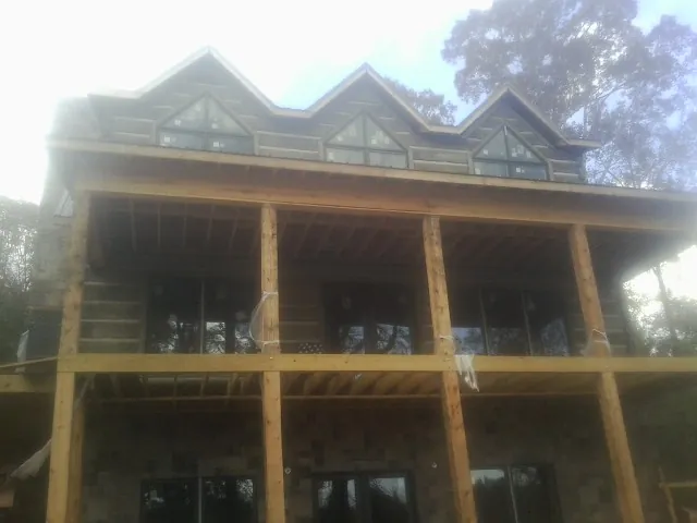 Dormers and porch framing on a large log home under construction — Roof Coating work by our crew in Calmar