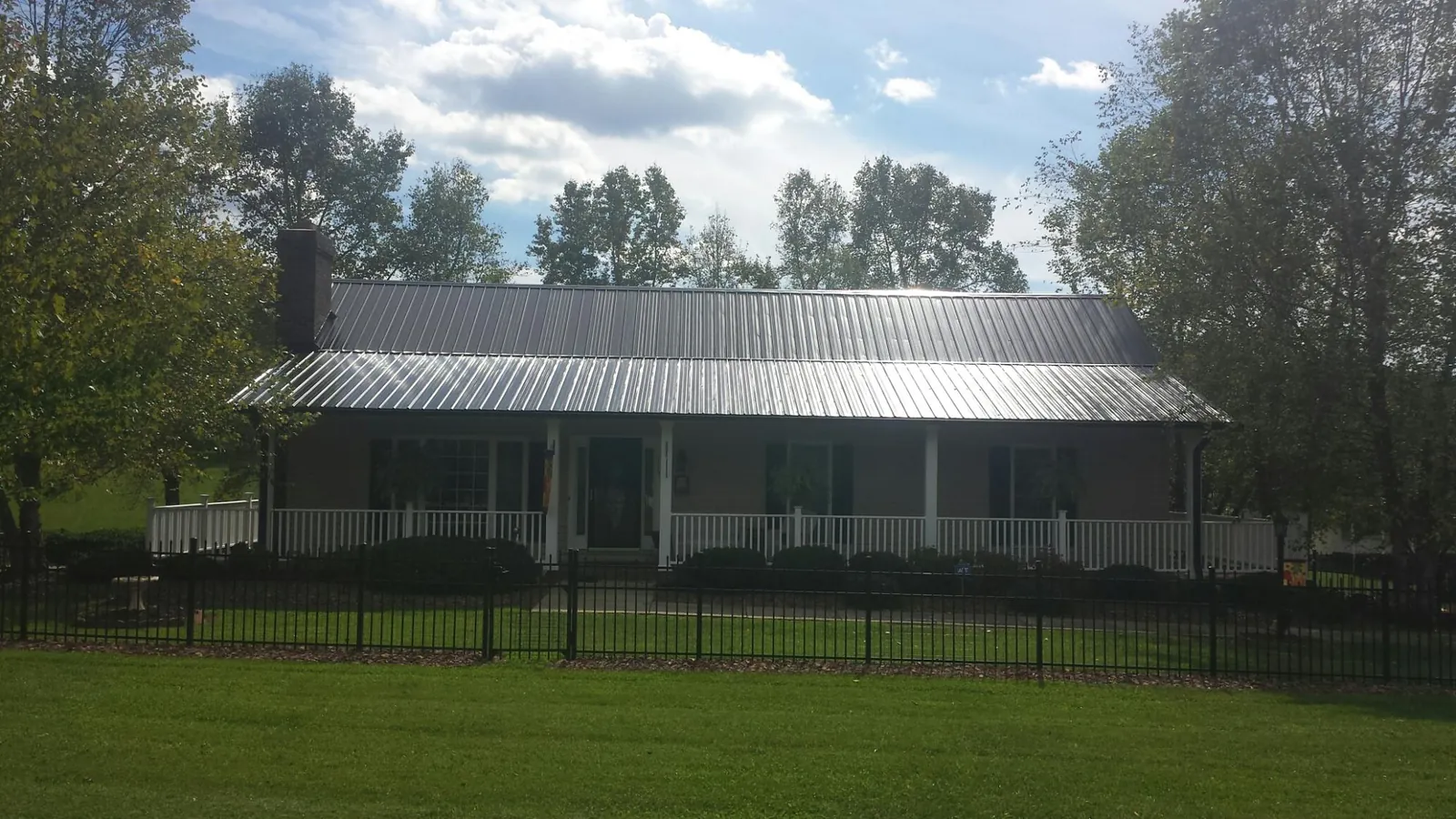 Gray metal roof on a brick ranch with a full width front porch — Gutter Guard Installation work by our crew in Calmar