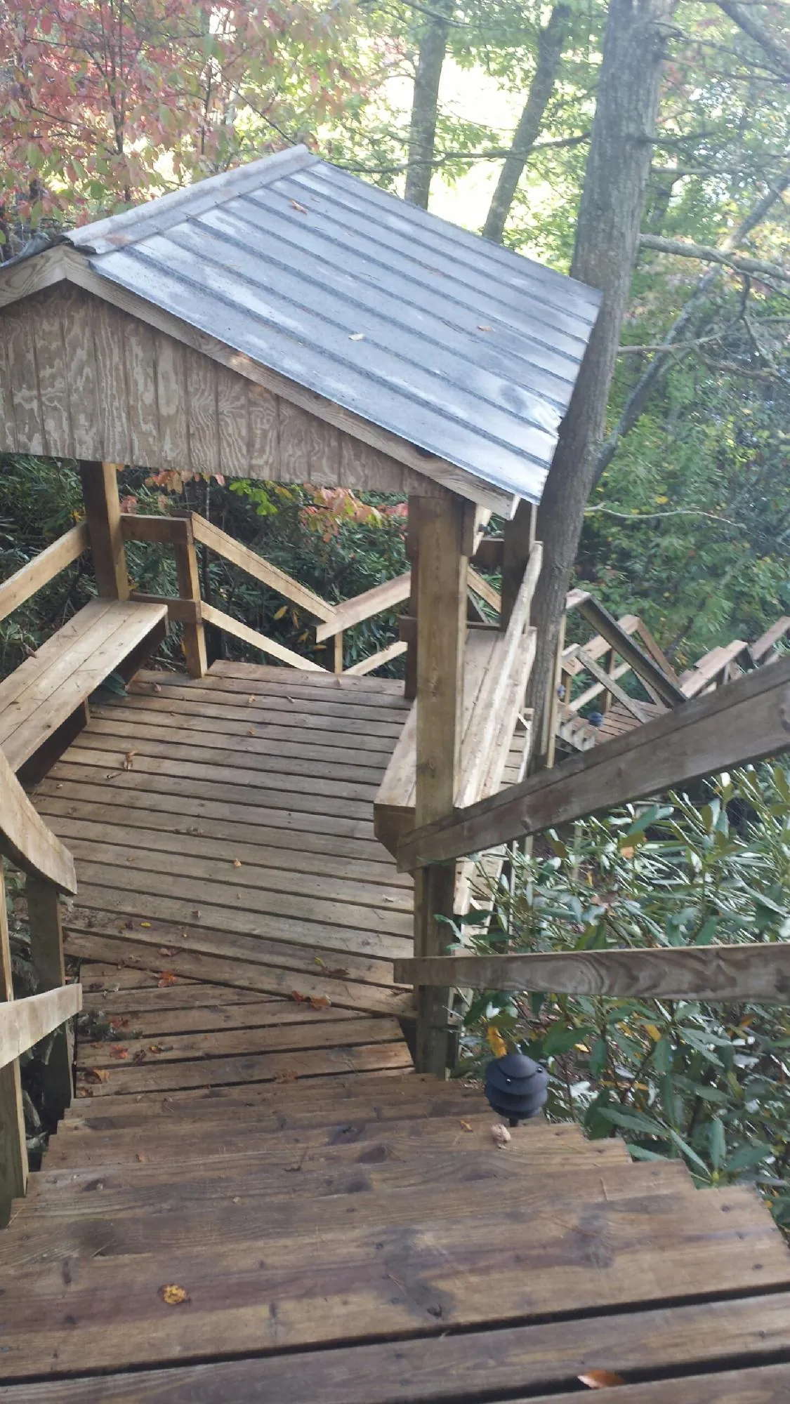 Metal roofed shelter over wooden steps on a wooded walkway — Skylight Repair & Installation work by our crew in Calmar